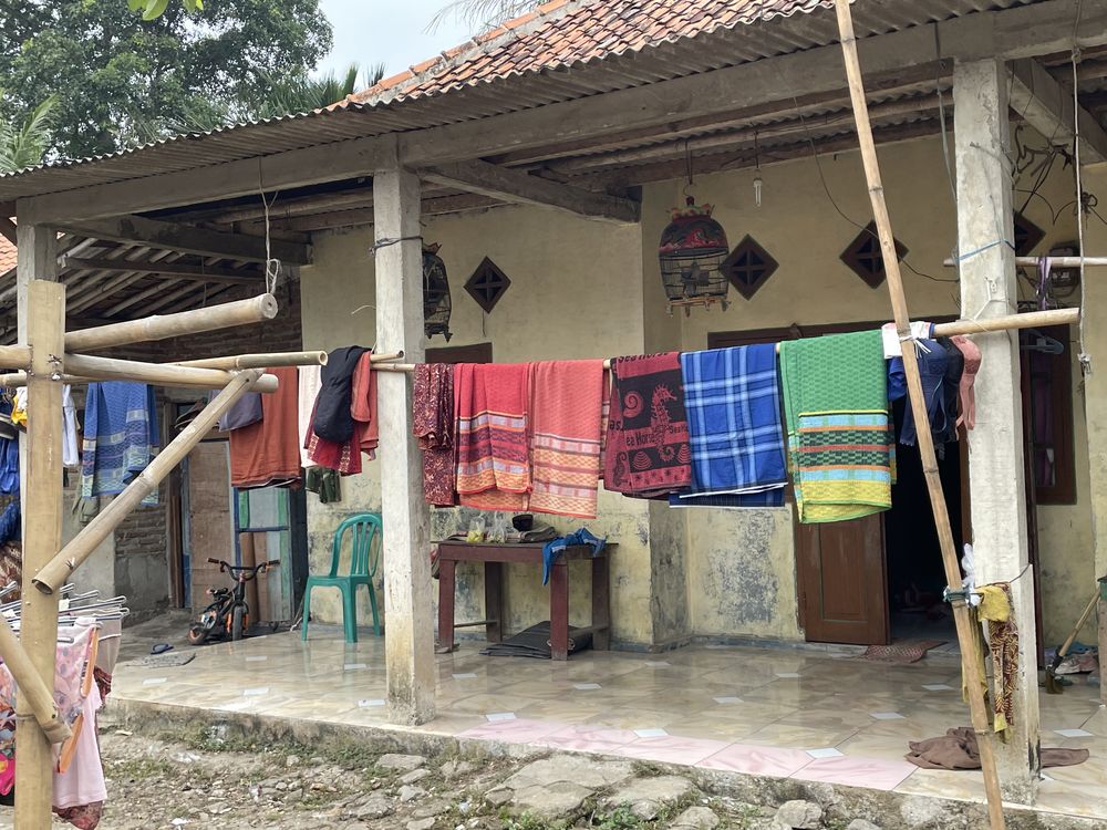 A family home with brightly coloured textiles drying on a line across the porch